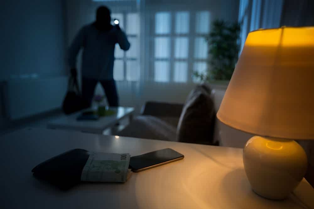 burglar with flashlight in unlit house